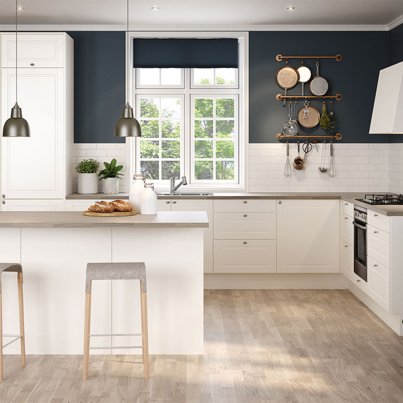 Lyst kjøkken med hvite skap, mørk blå vegg, kjøkkenøy med to trebarkrakker og hengende gryter