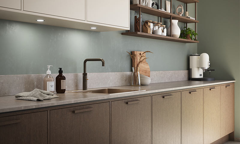 Moderne kjøkkenbenk i lyst tre, mintgrønn vegg, blandebatteri, såpedispensere og kaffemaskin