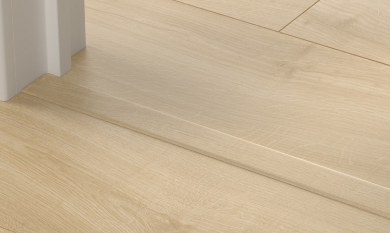 Lys eikegulv med terskel og hvit dørkarm.