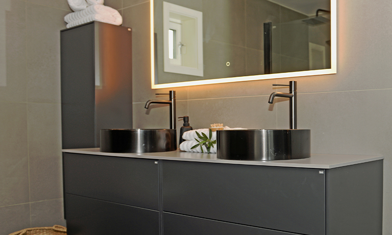 Moderne baderom med svart dobbelservant, opplyst speil og hvite håndklær