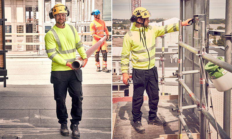 To arbeidere i neonfargede verneklær på byggeplass med stillas og byutsikt