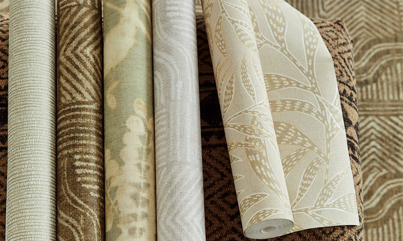 Seks tapetruller i brune og kremfargede nyanser med blad- og geometriske mønstre.