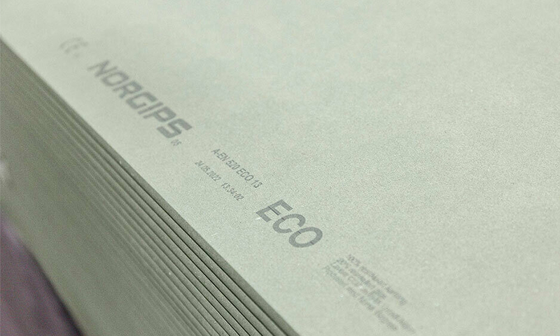 Nærbilde av stabler grønngrå gipsplater fra Norgips ECO med trykt logo.