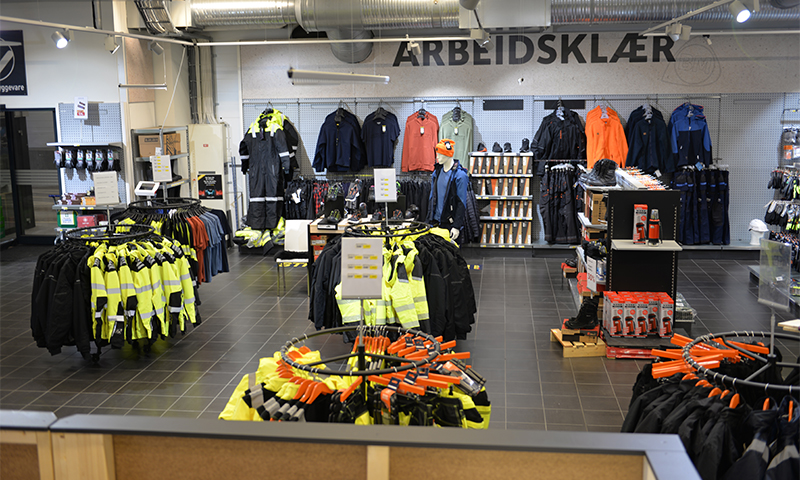 Butikkdel med arbeidsklær: gule refleksjakker, mørke jakker og mannekeng med hjelm