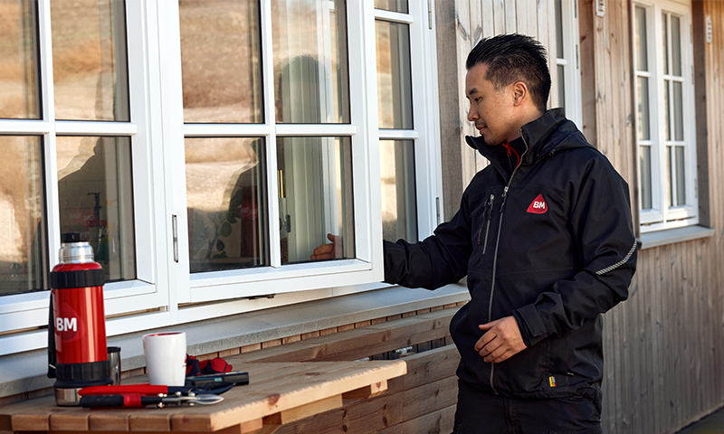 Mann utenfor bygning som ser på et hvitt vindu