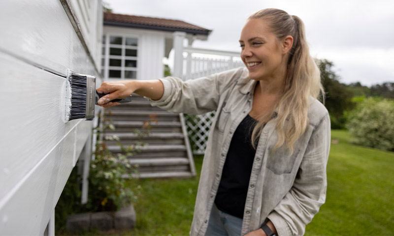 kvinne maler vegg hvit utendørs