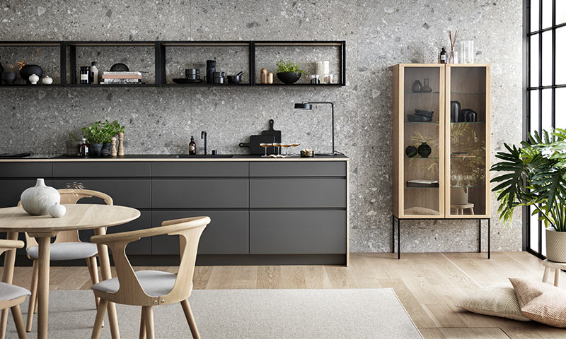 Moderne kjøkken i grått med eikegulv, trebord, åpen hylle, glasskabinett og grønn plante.