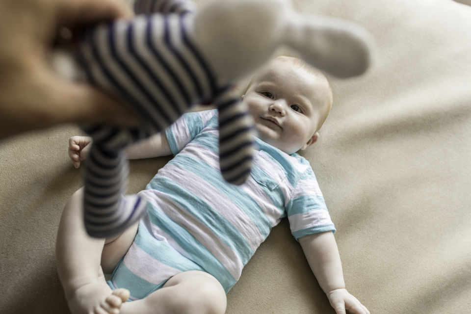 Stuffed animal being held over baby