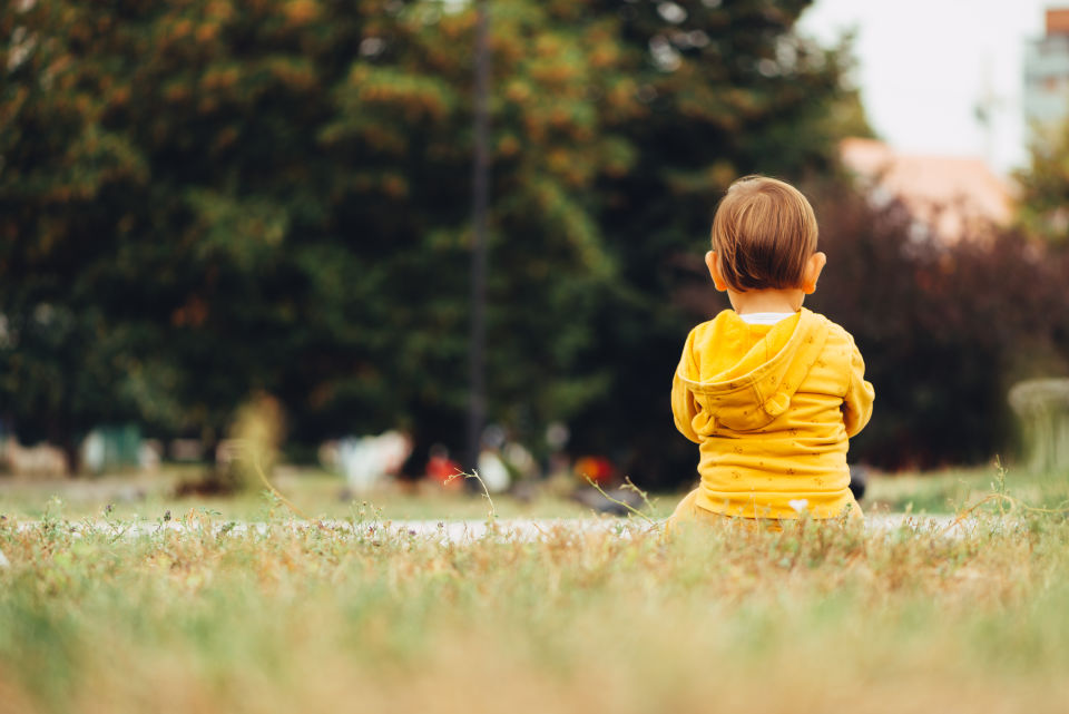 Boy wearing yellow shirt sitting on grass