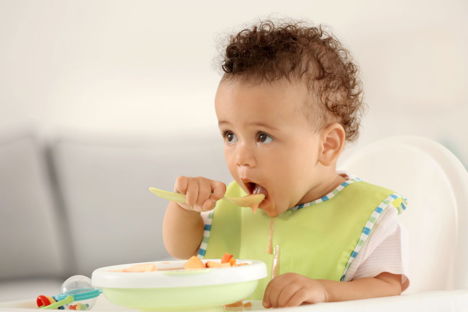 Baby boy eating soup wearing green bib