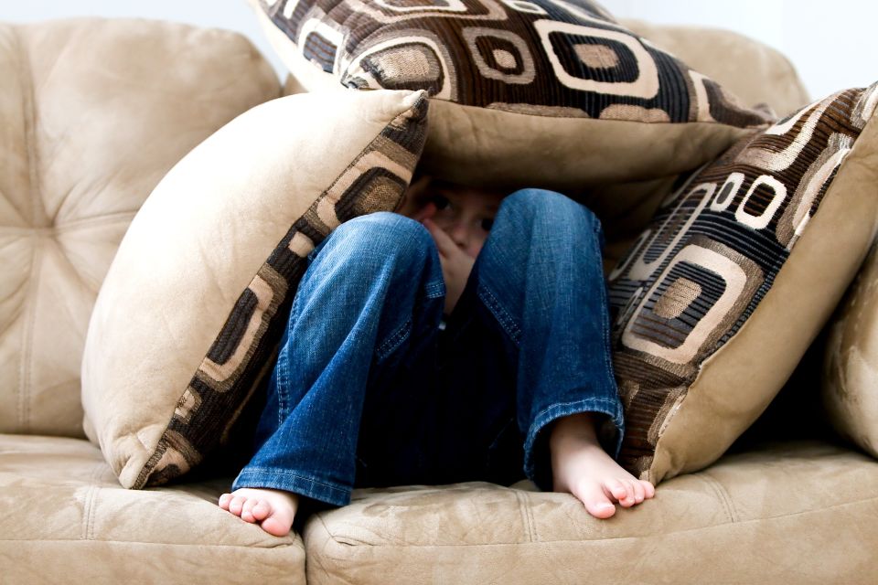 Kid sitting on couch with pillow fort