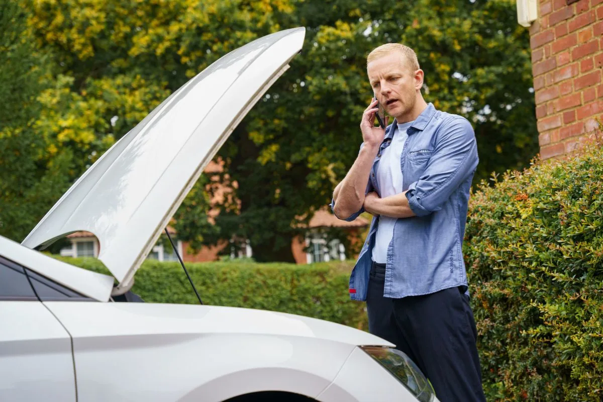 Man with car bonnet open on the phone