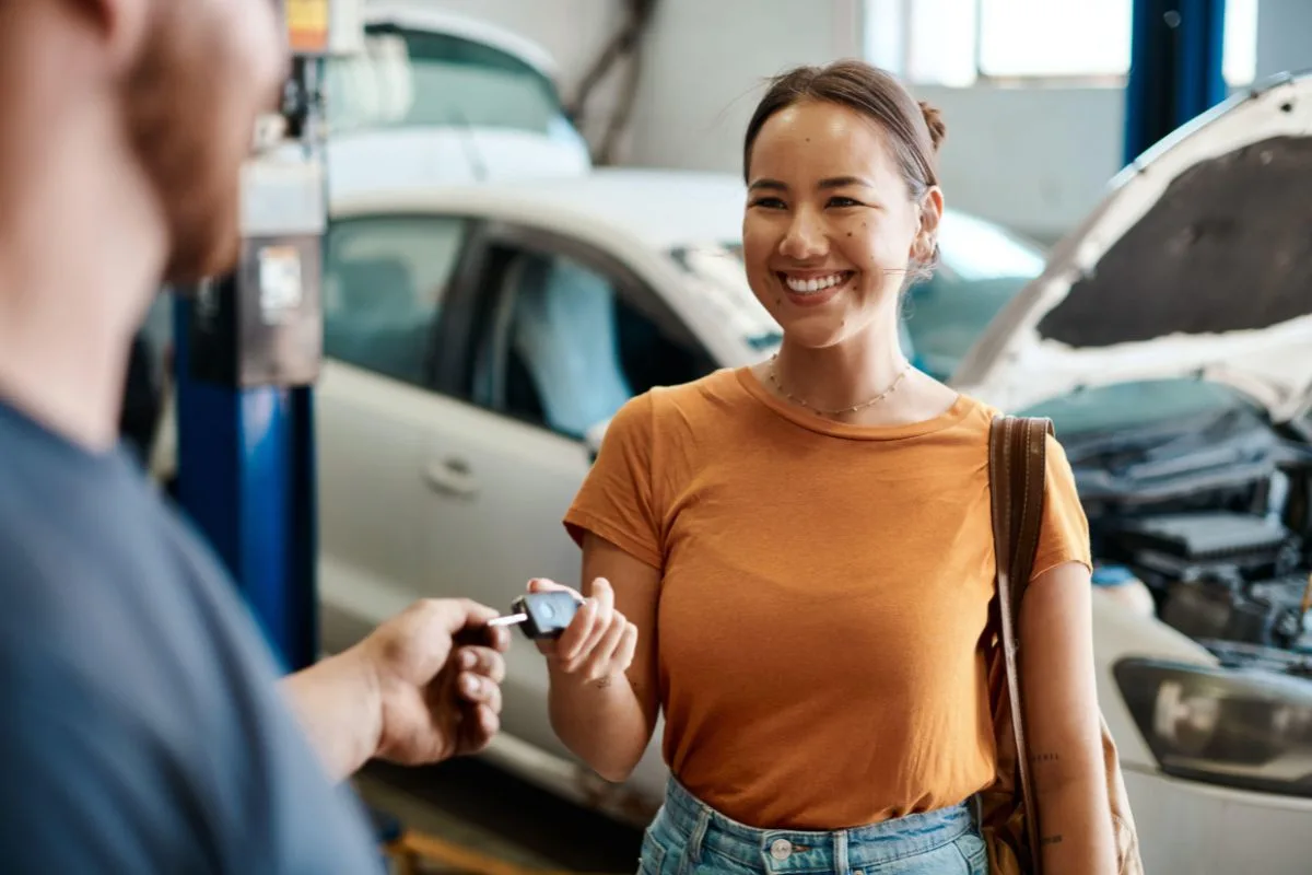 A woman in an orange top gets exchanges her car keys at a car garage