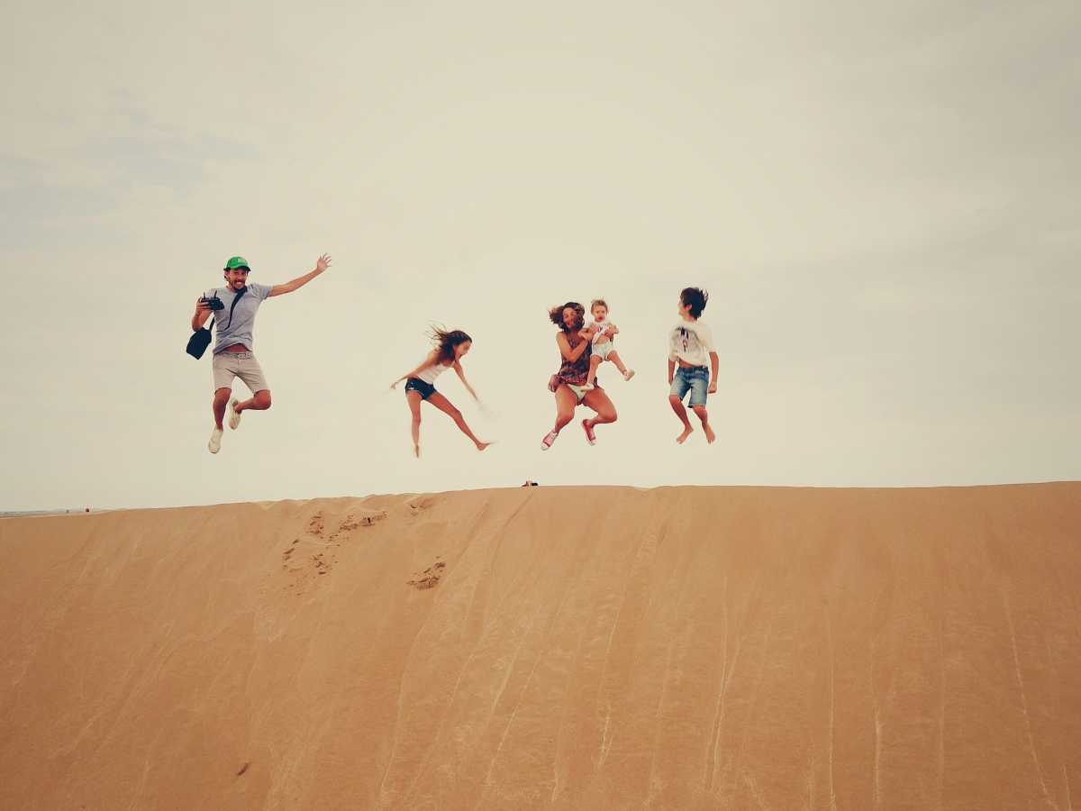 Family jumping on sand dune