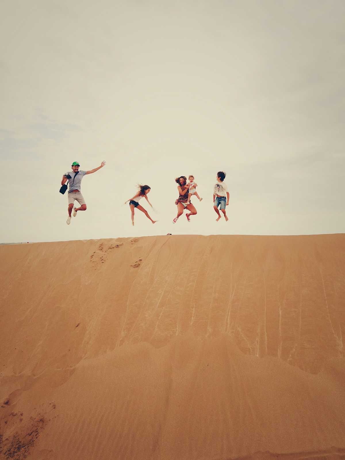 Family jumping on sand dune