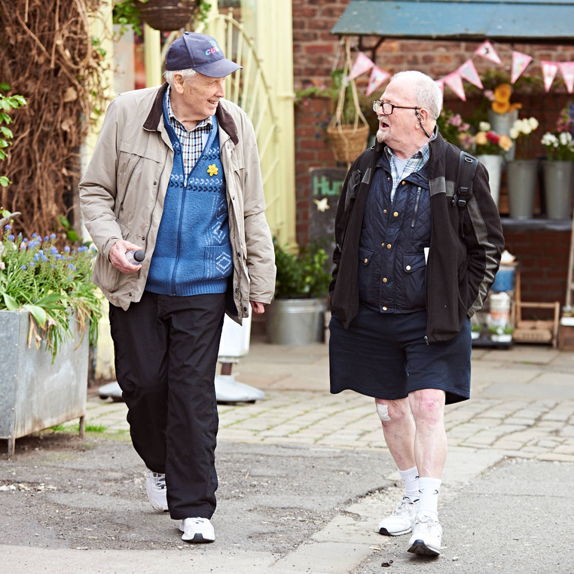 Two older men walking along a pedestrianised street