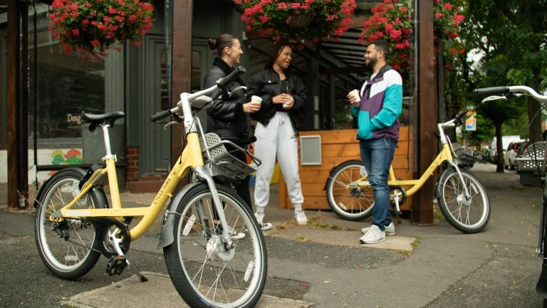 Three people stood having a chat next to their parked cycle hire bikes