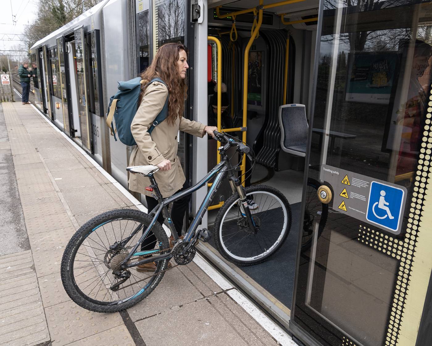 A woman getting on a tram with a bike