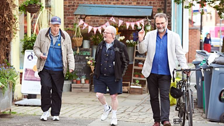 Three older men walking and laughing