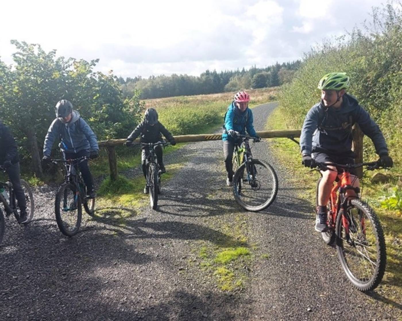 Group of young people wearing high viz cycling in a green area