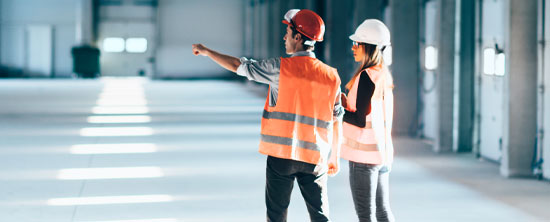 Two factory workers wearing safety gear in a warehouse