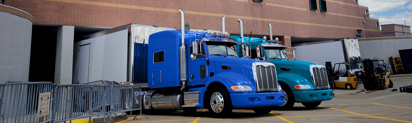 Two blue semi trailer trucks in dock area