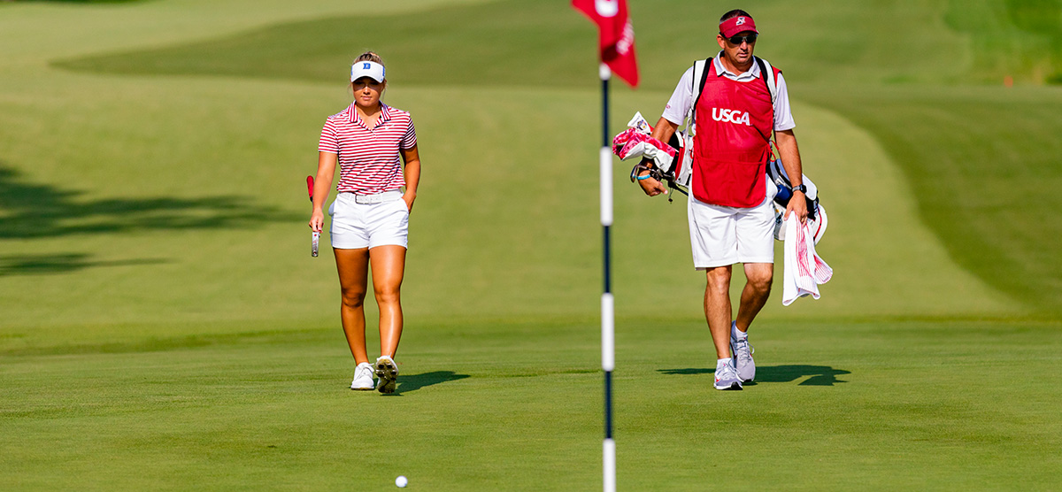 Erica Shepherd walking to green with caddy at the USGA championship at SentryWorld