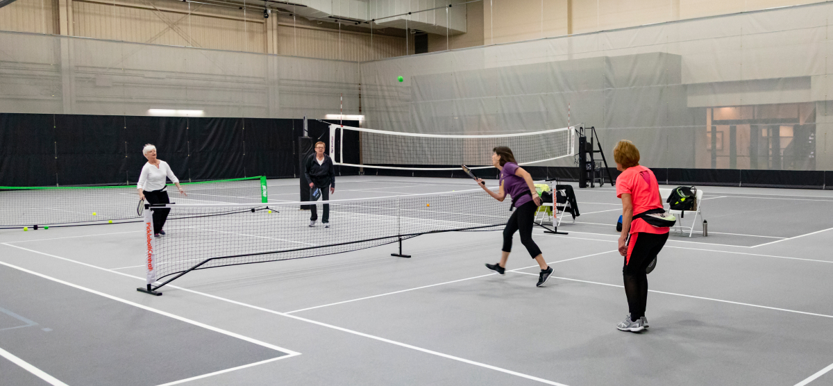 SentryWorld fieldhouse with four women playing pickleball on one court.