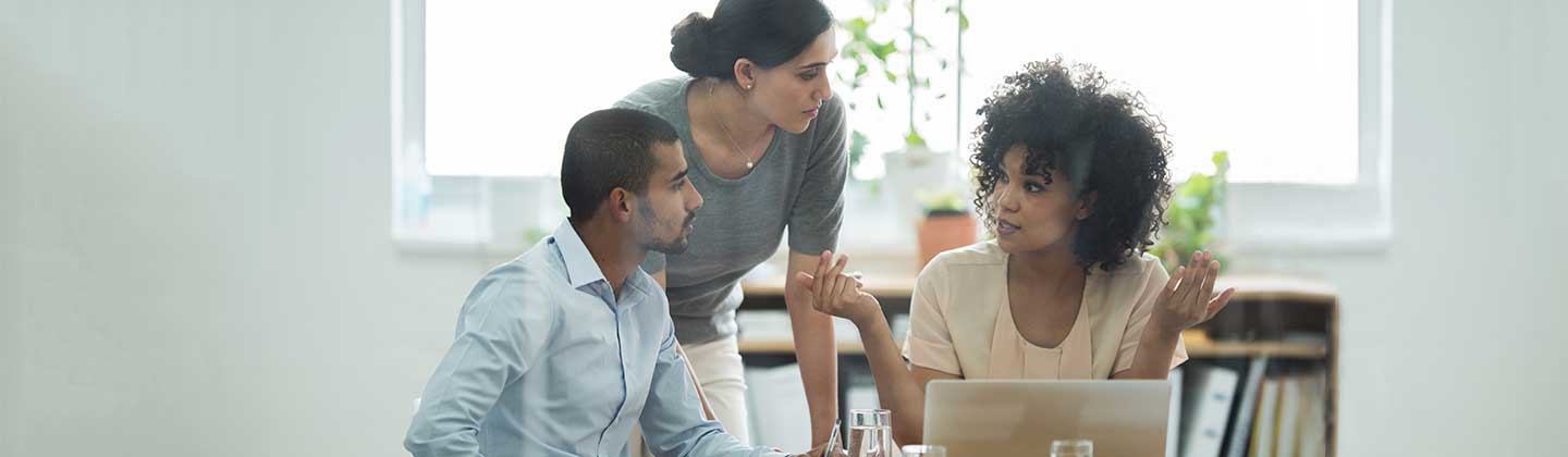 Three people around a laptop in discussion