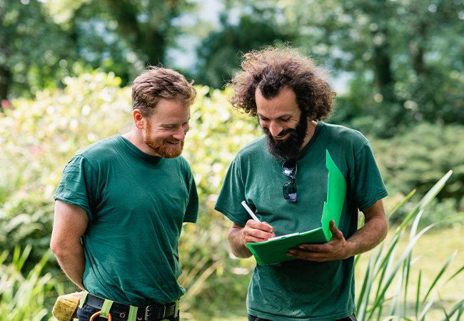 Two men talking near plants.