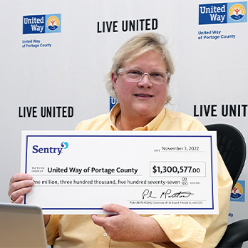 Woman holding Sentry donation check to United Way