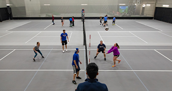 People playing volleyball on the courts in the fieldhouse at SentryWorld