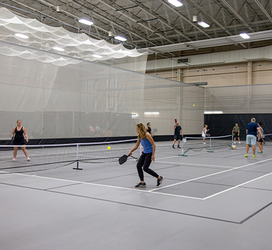 Fieldhouse pickleball courts with players playing pickleball. 