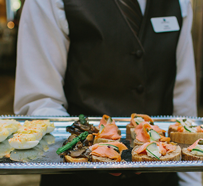 Staff serving a tray of finger foods for a wedding