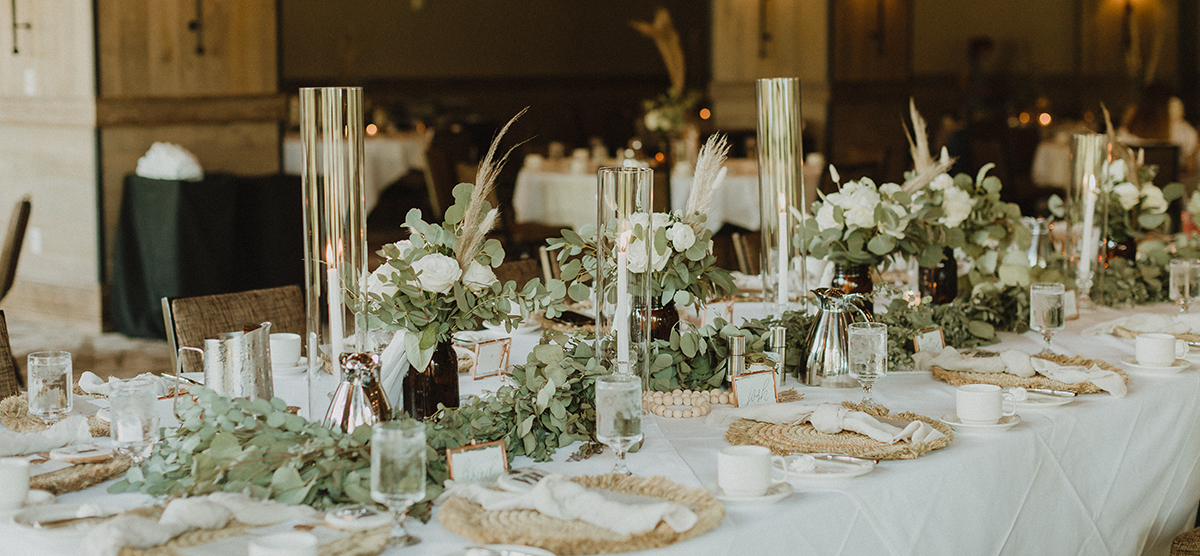 Greenery and table settings on the head table for a wedding reception