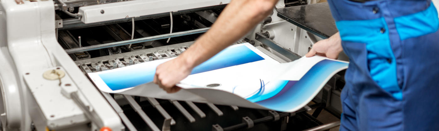 Worker pulling a sheet of paper from a printer