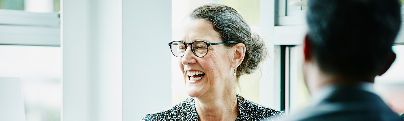 Woman in glasses laughing in meeting with someone