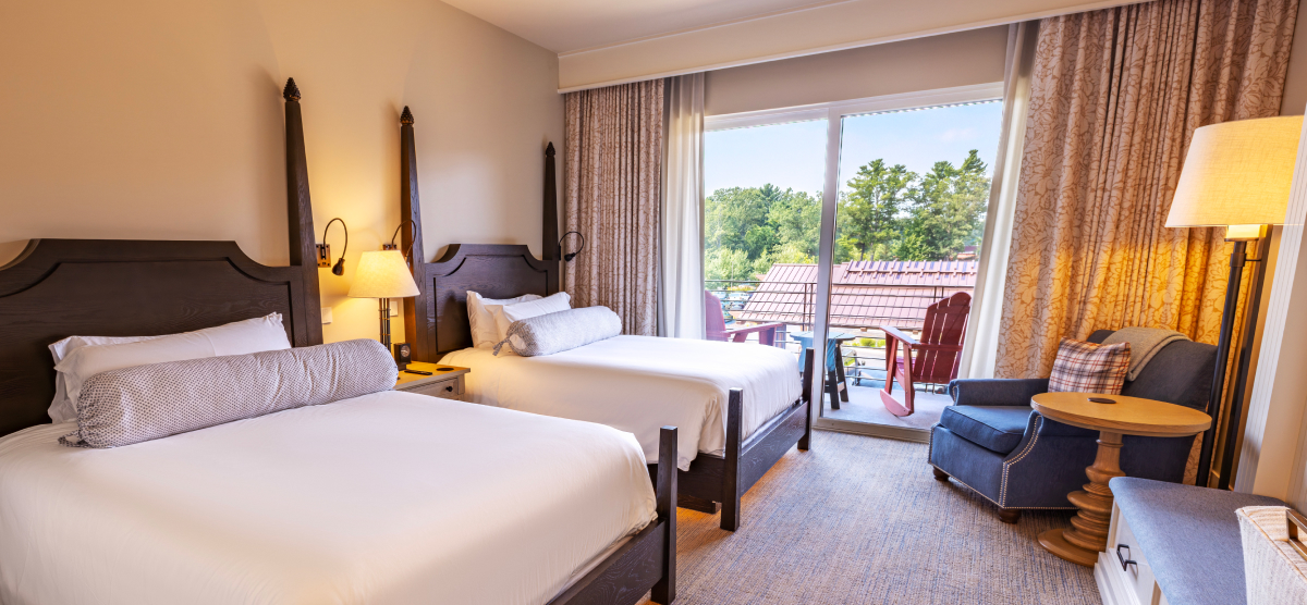 Hotel room with two beds and a balcony seating area. 