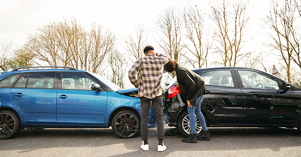 Young male and female inspecting damage after an accident.