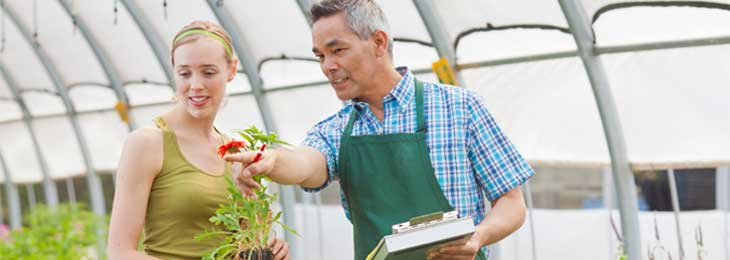 A man helping a woman at a greenhouse