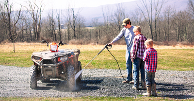 Man properly hosing down dirty ATV.