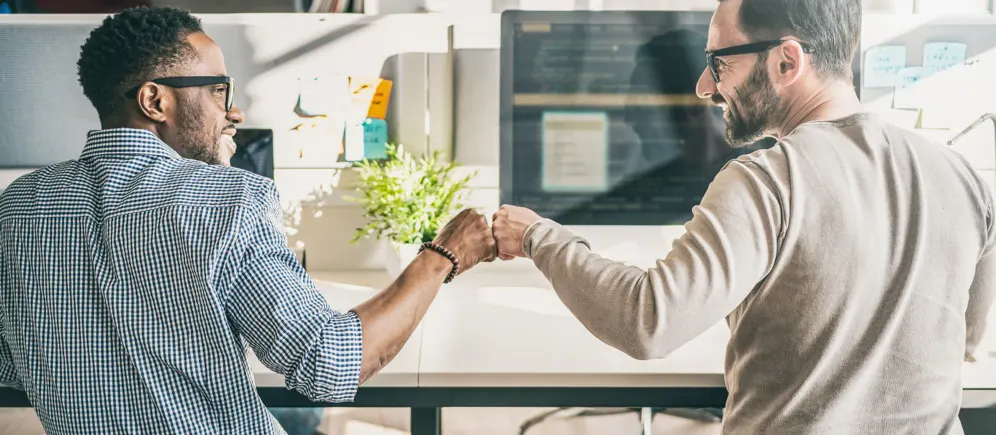 friends at work computers fist bumping