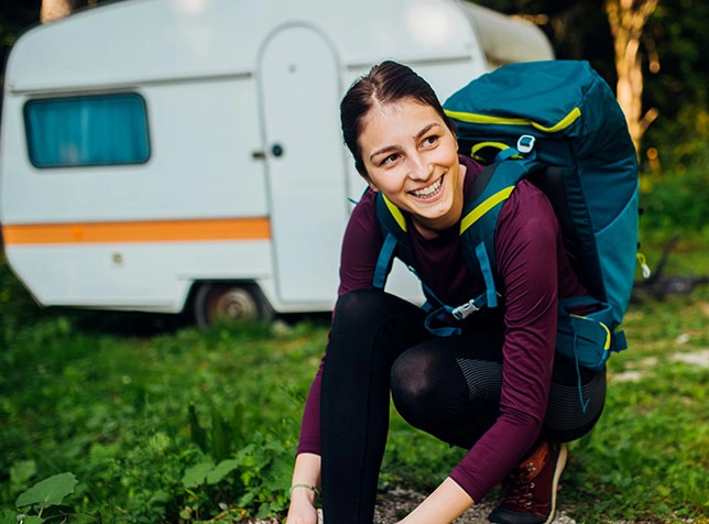 a woman next to her travel trailer preparing for a hike