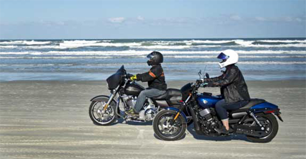 Two motorcycles being ridden on the beach