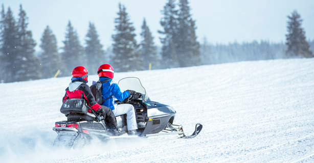 Couple snowmobiling on snowy hill