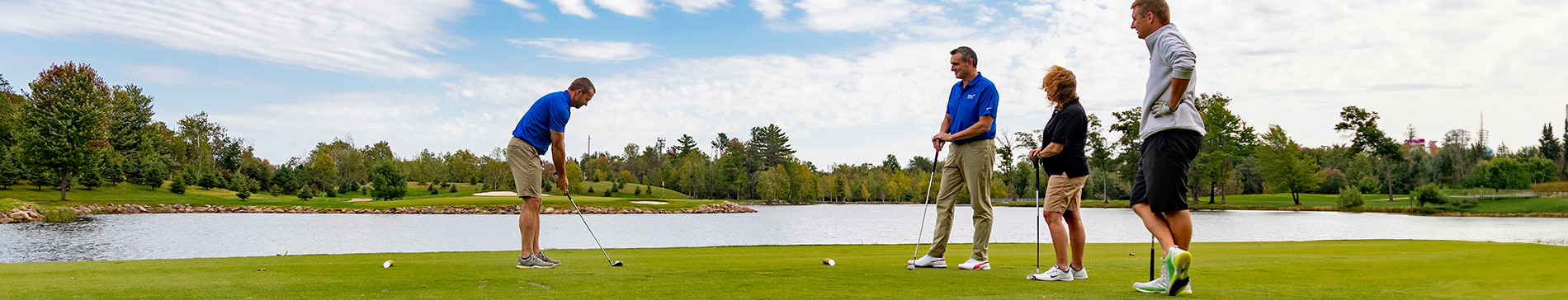 Four players teeing off on a tee box at SentryWorld