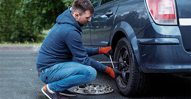 Man removing a flat tire from his car