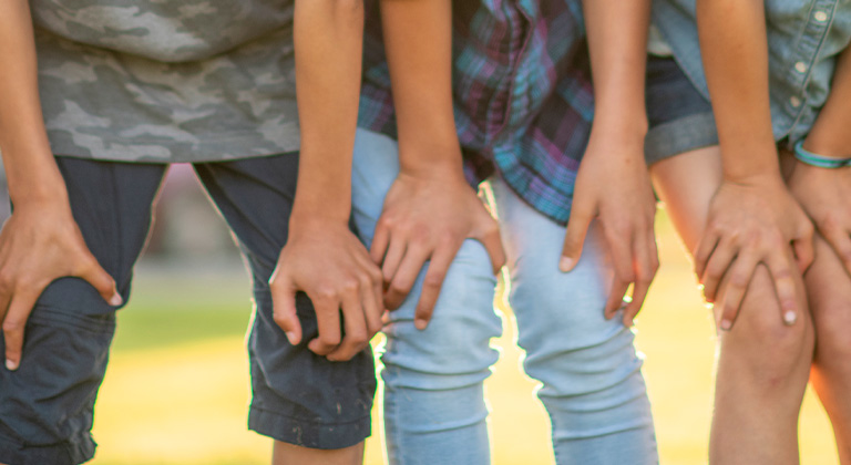 Three kids with their hands on their knees