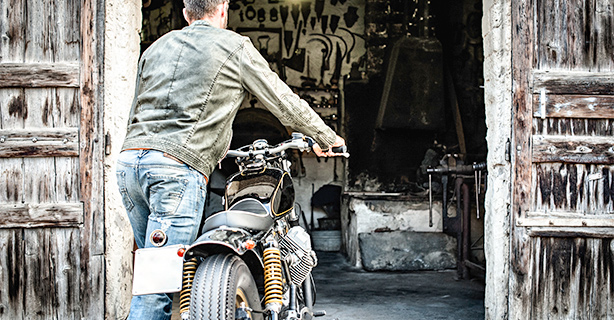 Man rolling a motorcycle into a garage