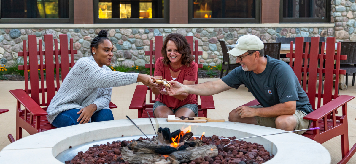 carousel-corporate-event-team-building-1-1200x556 Three people enjoy s'mores on The Inn patio.
